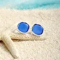 Close-up of blue sea glass stud earrings on white sand beach with a starfish background - Azure (HWG014-2)