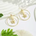 Détail de boucles d'oreilles créoles dorées avec pétales évidés et accents de perles - Bouton de Fleur Blanc avec Pétale 3D (HWX862-4)