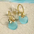 Detail of sea glass earrings with gold flower charms on white sand with a starfish - Light Blue Style (HWG018-1)