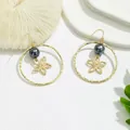 Détail de boucles d'oreilles anneaux dorés avec perles noires et fleurs ajourées - Perle Noire avec Fleur Évidée (HWX862-6)