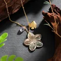 Detail of shell flower necklace with gold fish charm and purple gemstone on slate - Flower Fish Style (HWNX878ST-6)