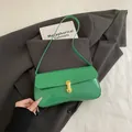 Green patent leather underarm bag with gold metal buckle on dark suit background - Green