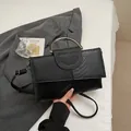 Elegante schwarze Handtasche in Krokodiloptik mit silbernem Metallgriff und Schultergurt - Schwarz