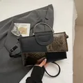 Schicke Handtasche aus schwarzem Leder mit Schlangenmuster und runden Metallgriffen - Braun