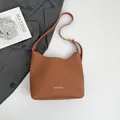 Brown lychee leather crossbody bag with adjustable strap and golden logo text - Brown
