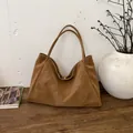 Bolso tote marrón de cuero suave con asas finas en un entorno de diseño minimalista - Marrón Sin Colgante