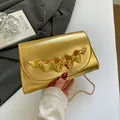 Goldene Saffiano-Umhängetasche mit Wellen-Metallverzierung und dünnem Kettenriemen - Flap Clutch Stil / Gold