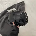 Black hobo shoulder bag with golden rivets in glossy finish and minimalist design - Black