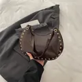 Dark brown crescent shoulder bag with glossy patent finish and golden stud details - Brown