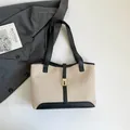 Bolso tote de lona beige con ribetes de cuero negro y cierre de metal dorado elegante - Negro
