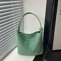 Sac seau vert en suédine avec broderie et poignée nouée dans un cadre minimaliste élégant - Vert