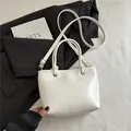 Minimalistische weiße Leder-Tote-Bag auf schwarzem Blazer, schicker Umhängetaschen-Stil - Weiß
