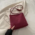 Schicke burgunderrote Wildleder-Eimertasche mit Knotengurten und eleganter Gravurverzierung - Rot