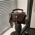 Borsa a tracolla vintage marrone scuro con finiture dorate mostrata in posa a mano - Marrone