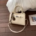 Beigefarbene Handtasche mit Lederstruktur, Umhängeriemen und kreativem Brezel-Anhänger - Weiß Mit Abakus Brezel Anhänger