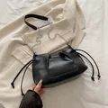 Schwarze plissierte Umhängetasche mit silberner Kette auf beigem Blazer - Schwarz
