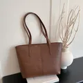 Braune Tragetasche aus Kunstleder mit Krokoprägung und langen Henkeln auf Buch - Einfache Tote Bag / Braun Ohne Anhänger