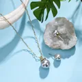 Detailed macro view of gold chain necklace and grey pearl earrings on blue background - Gray (HWNX8841-11)