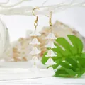 Detail of hanging lily of the valley earrings with white resin flowers and gold hooks - Long
