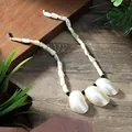 Detailopname van Hawaiiaanse schelpenketting met parelmoer hangers op houten ondergrond - 3 Grote Halve Maan Schelpen Stijl(HWBN904)