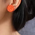 Handmade round woven rattan earrings in vibrant orange shown on a female model - Orange Round Woven Style (PLE1796)