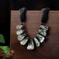 Detailopname van iriserende abalone schelpenketting met zwarte kralen op hout - Natuurlijke Iriserende Abalone Schelp Stijl (HWBN813)