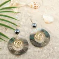 Detail of shell earrings featuring golden dolphin charms on a sandy beach background - Heart Dolphin Style (HWB4321-2)