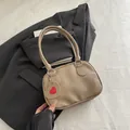 Minimalistische khakifarbene Handtasche mit Herzanhänger auf schwarzem Anzughintergrund - Khaki
