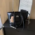 Glossy black leather tote bag with a small plush bear charm in a chic indoor setting - With Pendant / Black