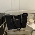 Bolso tote de pana negra con correas de cuero y etiqueta minimalista en estante - Negro