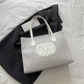 White tote bag with grey M monogram print and slim shoulder straps on a clean background - White