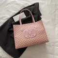 Pink tote bag with monogram print and large embossed logo on a black blazer background - Pink
