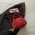 Red crossbody bag with silver rivets and matte leather texture on dark background - Red