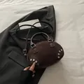 Dark brown suede crossbody bag with silver rivet details on grey blazer background - Brown