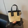 Minimalist beige canvas bucket bag with black leather straps and gold metal hardware - White and Black