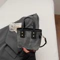 Mini gray denim bucket bag with black handles and gold buckles on a minimalist background - Dark Brown