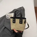 Khaki bucket bag with black trim and gold rivets shown on a stylish grey blazer - White & Black