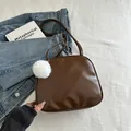 Brown leather travel cosmetic bag with white fluffy charm on casual denim background - With Pendant / Brown