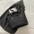 Black polka dot tote bag with small white bows on a textured fabric surface - Black