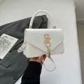 White patchwork crossbody bag with woven texture, gold metal accents and tassel detail - White