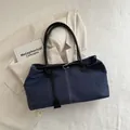 Borsa tote in denim blu scuro con cinturini neri e fibbia metallica su giacca crema - Blu scuro