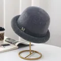 Detail of grey plush bucket hat with a gold metal M letter on a stylish gold stand - M (56-58cm) / Gray (With M Logo)
