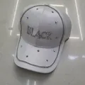 Detailansicht der weißen Baseballkappe mit BLACK-Strassbuchstaben und Kettenverzierung - Satin Weiß