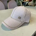 Close-up of pink tweed baseball cap featuring shiny rhinestones and a gold metal M logo - Pink