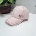 Detailed texture of pink tweed baseball cap featuring a golden metallic M logo - Pink