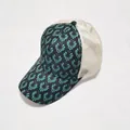 Detail van de blauwgroene bloemenprint en ademend gebroken wit gaas op de trucker pet - Geometrische Bloemenstijl