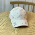 Detail of NYC rhinestone lettering on plush cream-white baseball cap on wooden table - Adult Size (Adjustable) / White