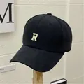 Schwarze Baumwoll-Baseballkappe mit besticktem Buchstaben R auf einem Holzständer - Einheitsgröße(Einstellbar) / Schwarz