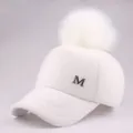 Detailed view of white plush baseball cap with fluffy faux fur pompom and metal M logo - Adult / White