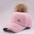 Detailed macro view of pink fuzzy baseball cap with fluffy fur pompom and metal M logo - Adult / Pink Hat with Camel Pom Pom